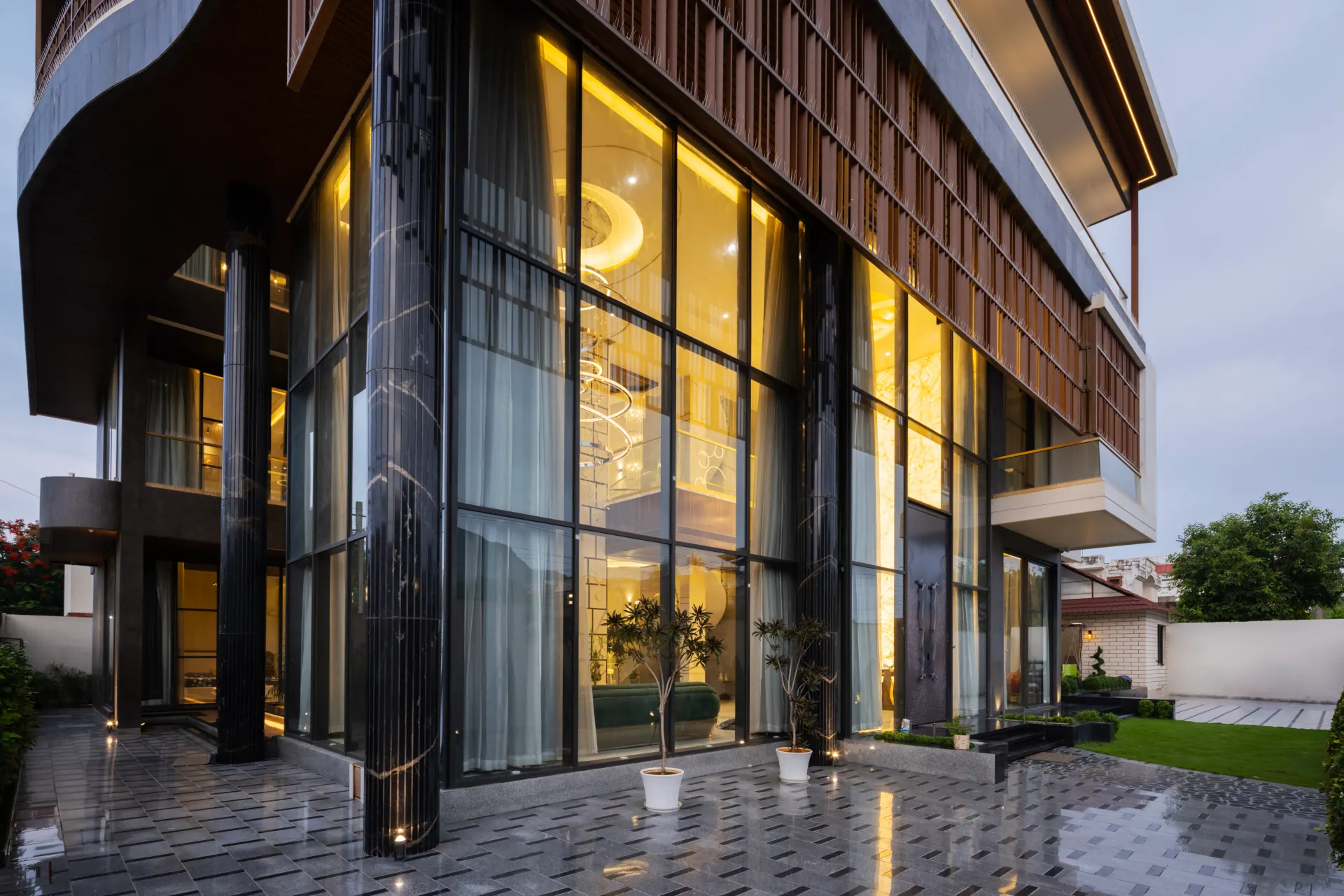 Modern home exterior with tall aluminium glazing lit at dusk